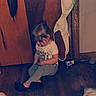 toddler, child, wooden_floor, wooden_door, bra, red_plate, sitting, indoors, casual_clothing, tshirt, leggings, footwear, hair, head_down, quiet, floor, door, room, home, childhood