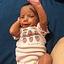 Torianna joined the competition — help win amazing prizes! baby, infant, child, onesie, strawberry_print, pink_clothing, blue_background, raising_hand, lying_down, cute, expression, skin, face, arm, hand, person, newborn, casual, indoor, playful