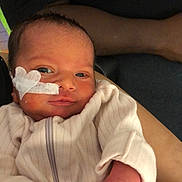 Torianna is registered to the contest to win money with this photo: newborn, baby, infant, face, medical_tape, heart_shape, clothing, hand, person, arm, portrait, closeup, skin, eyes, sleeve, zipped_jumper, human, cute, indoors, resting
