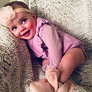 Mi Amor is registered to the contest to win money with this photo: baby, child, infant, smile, headband, flower, purple_clothing, polka_dots, blanket, soft_texture, booties, cute, happy, cozy, indoors, portrait, sitting, face, skin, cheeks