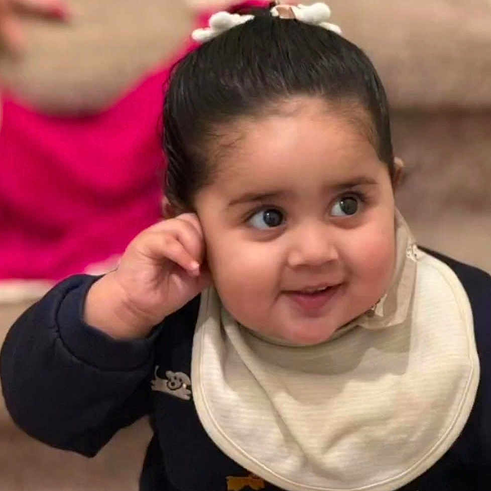 Mehareen is registered to the contest to win money with this photo: baby, background_blur, bib, child, clothing, curly_hair, cute, dark_sleeves, expression, face, hand, happy, head, indoor, portrait, sitting, skin, smile, toddler, young_child