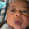Elias is registered to the contest to win money with this photo: baby, close_up, face, expression, infant, puckered_lips, wide_eyes, skin, person, newborn, cute, portrait, indoor, blanket, fabric, head, young, child, mouth, nose