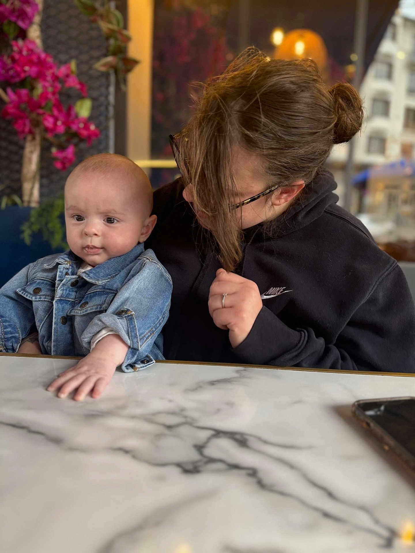 Louka a rejoint le concours — aidez-le/la à gagner de superbes lots ! baby, child, woman, denim_jacket, black_hoodie, glasses, table, marble, flower, plant, indoor, portrait, person, urban, window, hand, face, casual_clothing, curious, seated