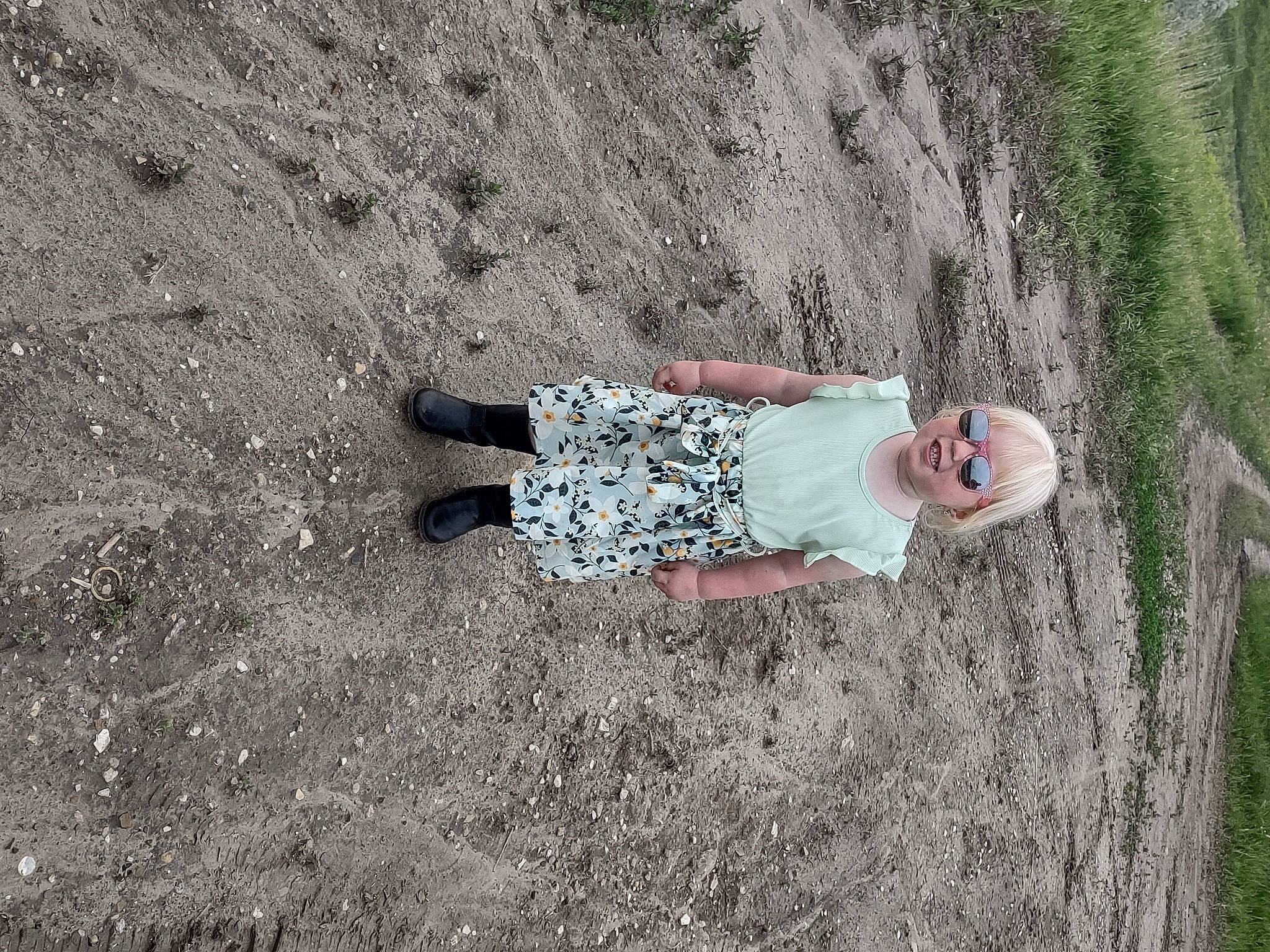 Clarissa is registered to the contest to win money with this photo: asphalt, concrete, fun, grass, grassland, grey, happy, human_leg, landscape, leisure, people_in_nature, person, plant, recreation, road_surface, rock, shadow, sitting, soil, tree