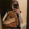 brown_cat, casual_clothing, cat, curious_cat, door, floor, glasses, holding, home, indoor, jeans, mirror, paper_bag, person, phone, reflection, selfie, shoes, striped_sweater_vest, wall