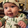 Roman joined the competition — help win amazing prizes! baby, infant, child, cute, close_up, hat, clothing, forest_pattern, animal_print, hand, face, eyes, mouth, indoor, furniture, blurry_background, toy, smile, person, portrait