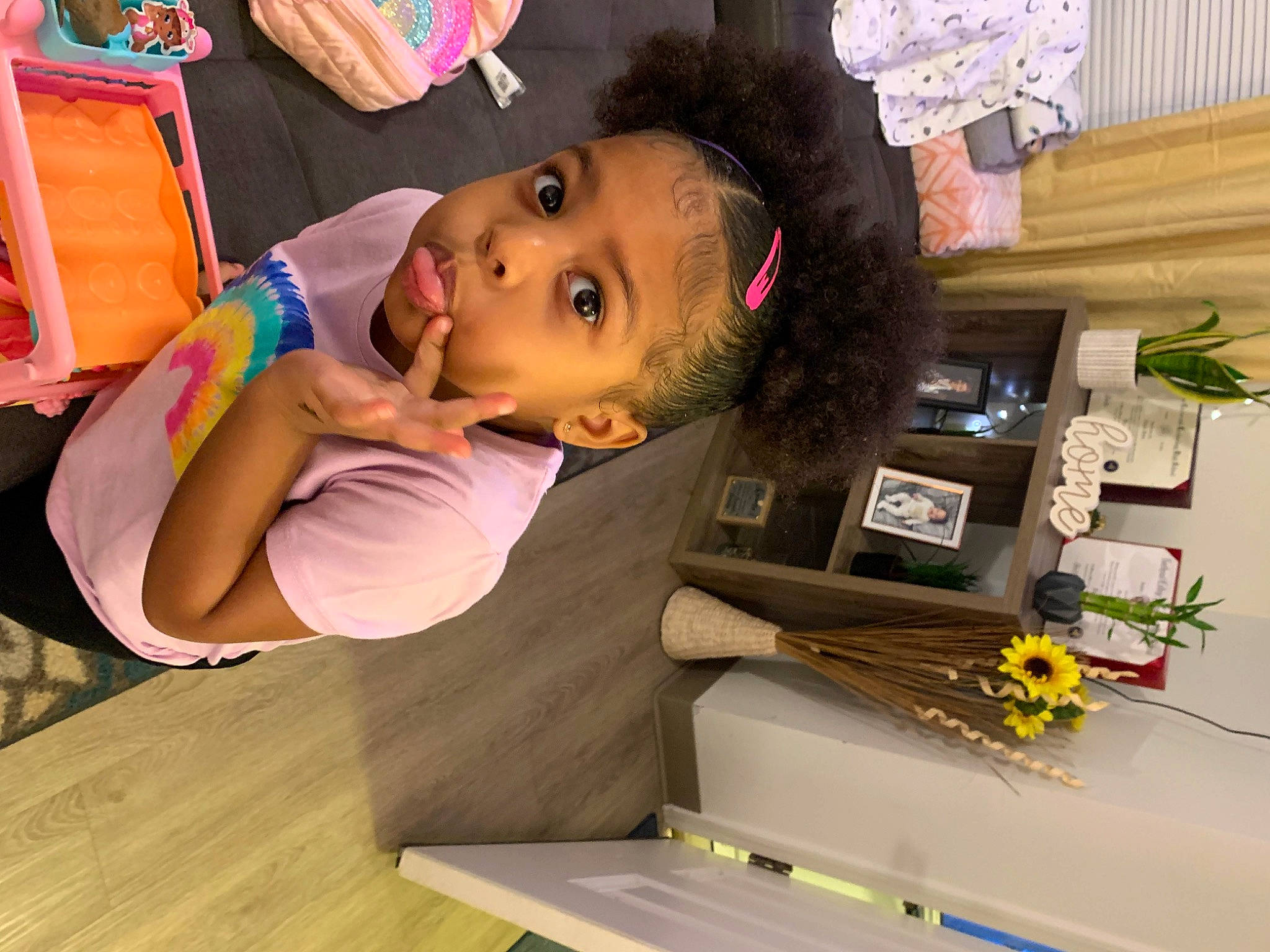 Malanhi is registered to the contest to win money with this photo: chair, curtain, flooring, flower, fun, happy, hardwood, hat, houseplant, party, person, picture_frame, plant, play, room, t_shirt, table, thigh, toddler, wood