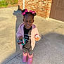child, girl, pink_bows, pink_boots, sippy_cup, pacifier, outdoor, sunny, concrete, brick_wall, smiling, happy, clothing, cute, standing, person, toddler, hair_buns, casual, daylight
