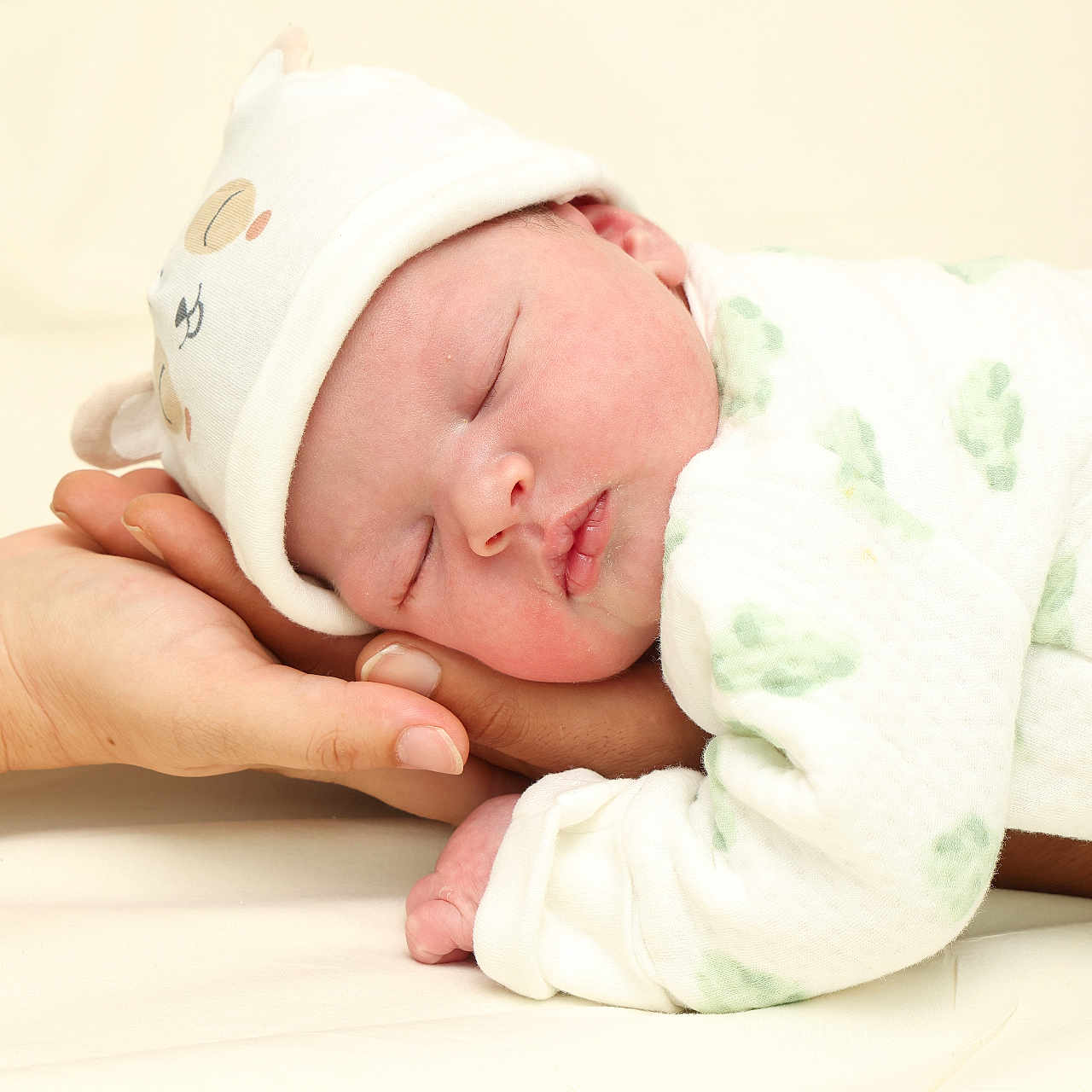 Yanis participe au concours pour gagner de l'argent avec cette photo : adult_hand, baby, baby_clothes, bed, closeup, cozy, cute, green_pattern, hand, hat, infant, newborn, peaceful, portrait, resting, skin, sleeping, soft, tender, white_clothing