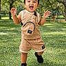 toddler, child, smiling, happy, outdoor, park, playground, grass, trees, portrait, standing, running, walking, hands_raised, open_mouth, short_hair, tan_outfit, overalls, backpack, shoes