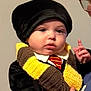 Beau joined the competition — help win amazing prizes! baby, infant, child, person, hat, knitted_scarf, scarf, striped_tie, glasses, adult_hand, portrait, costume, indoors, wall_background, closeup, holding, cute, neutral_expression, black_clothing, yellow_brown
