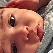 Beau is registered to the contest to win money with this photo: baby, infant, close_up, face, eye, lips, cheek, nose, eyelashes, blanket, soft_texture, portrait, relaxed, cozy, skin, detail, hand, fuzzy_blanket, natural_light, intimate