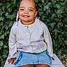 beads, braided_hair, casual, child, cute, daylight, denim_skirt, fashion, greenery, happy, ivy, nature, outdoor, person, portrait, sitting, smiling, sweater, white_crate, young