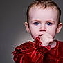 baby, child, portrait, face, blue_eyes, red_dress, velvet, hand, thumb, curious, innocent, close_up, studio_lighting, soft_background, cute, young, expression, person, sitting, fashion