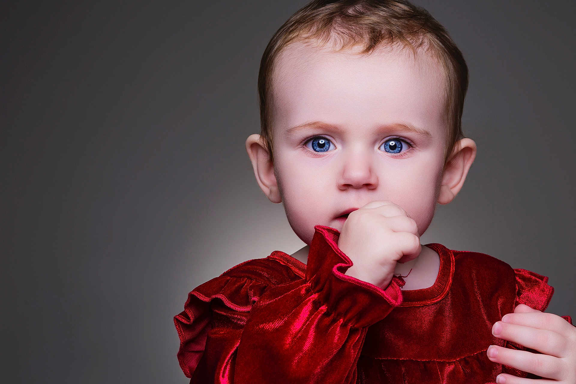 Josie joined the competition — help win amazing prizes! baby, child, portrait, face, blue_eyes, red_dress, velvet, hand, thumb, curious, innocent, close_up, studio_lighting, soft_background, cute, young, expression, person, sitting, fashion