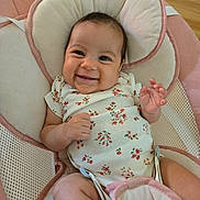 Ashley is registered to the contest to win money with this photo: baby, smiling, infant, onesie, floral_pattern, baby_seat, cushion, pink, cream, happy, child, cute, indoors, person, portrait, skin, hand, face, head, wood_floor