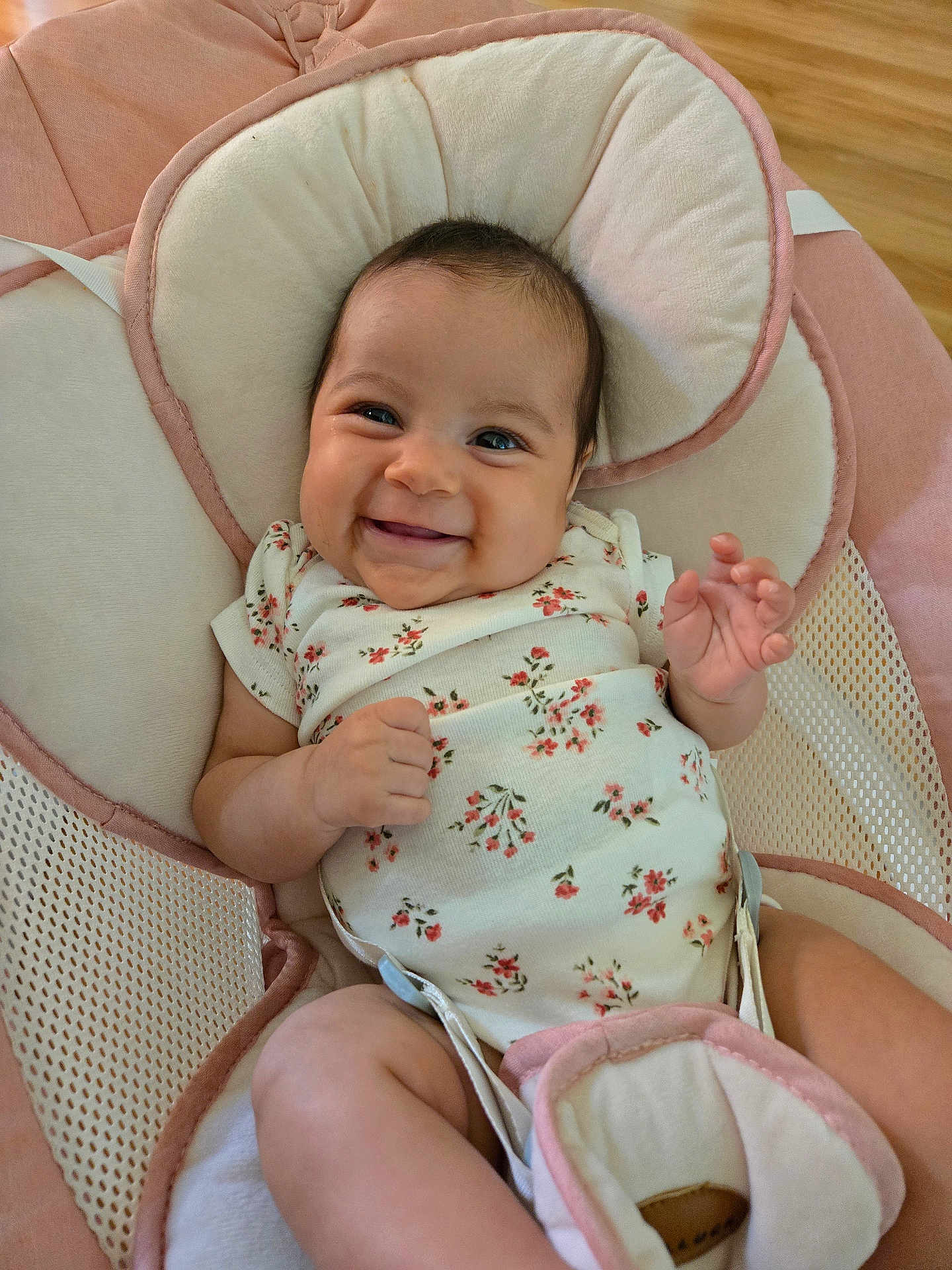 Ashley is registered to the contest to win money with this photo: baby, smiling, infant, onesie, floral_pattern, baby_seat, cushion, pink, cream, happy, child, cute, indoors, person, portrait, skin, hand, face, head, wood_floor