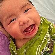 Kenton is registered to the contest to win money with this photo: baby, child, smiling, happy, face, mouth_open, green_shirt, striped_clothing, person, infant, joy, cute, portrait, close_up, skin, head, eyes, tongue, sitting, indoor