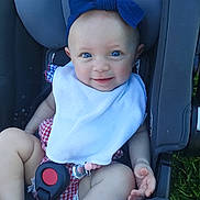 Adalynn is registered to the contest to win money with this photo: baby, child, stroller, smiling, blue_bow, bib, checkered_outfit, sitting, portrait, outdoor, greenery, infant, face, eyes, happy, sunlight, baby_clothing, safety_harness, vehicle_seat, photography