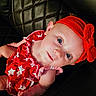Adalynn is registered to the contest to win money with this photo: baby, child, infant, portrait, face, blue_eyes, smiling, red_outfit, star_pattern, headband, bow, seated, lying_down, black_chair, leather, indoor, close_up, cute, photography, holiday_style