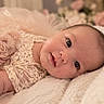 baby, infant, child, portrait, lying_down, smiling, wide_eyes, face, close_up, lace_outfit, dress, pink, blanket, soft_texture, bed, indoor, cozy, floral, photography, adorable