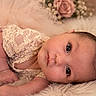 baby, infant, child, portrait, lying_down, wide_eyes, face, smiling, fluffy_blanket, lace_clothing, pink_tulle, roses, flowers, soft_lighting, indoor, newborn_photography, close_up, cute, cozy, photography