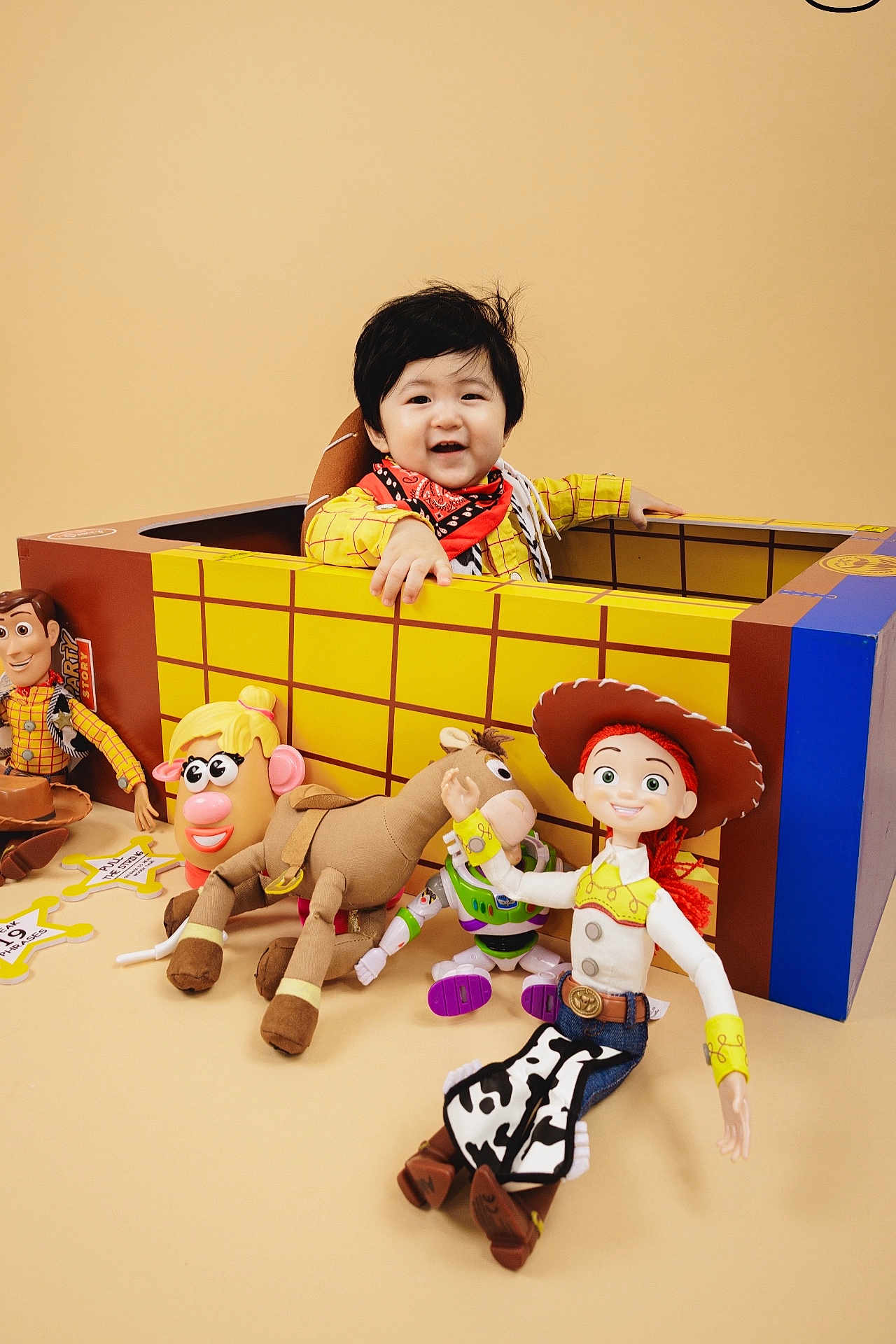 Liam joined the competition — help win amazing prizes! child, toddler, baby, smiling, cardboard_box, toys, woody, jessie, buzz_lightyear, mr_potato_head, bullseye, plush_toy, bandana, cowboy_costume, playtime, beige_background, indoor, portrait, happy, face