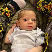 Grace is registered to the contest to win money with this photo: baby, infant, couch, clothing, onesie, person, legs, socks, patterned_pants, snake_pattern, texture, indoor, portrait, young_child, cute, wide_eyes, resting, hand, fabric, casual