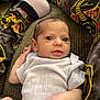 baby, infant, couch, clothing, onesie, person, legs, socks, patterned_pants, snake_pattern, texture, indoor, portrait, young_child, cute, wide_eyes, resting, hand, fabric, casual
