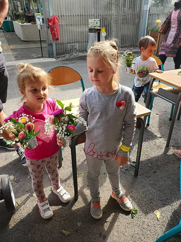 Imola participe au concours pour gagner de l'argent avec cette photo : chair, child, daytime, event, fashion, flower, flower_arranging, flowerpot, fun, grass, leaf, mammal, person, pink, plant, pole, public_space, social_group, spring, summer