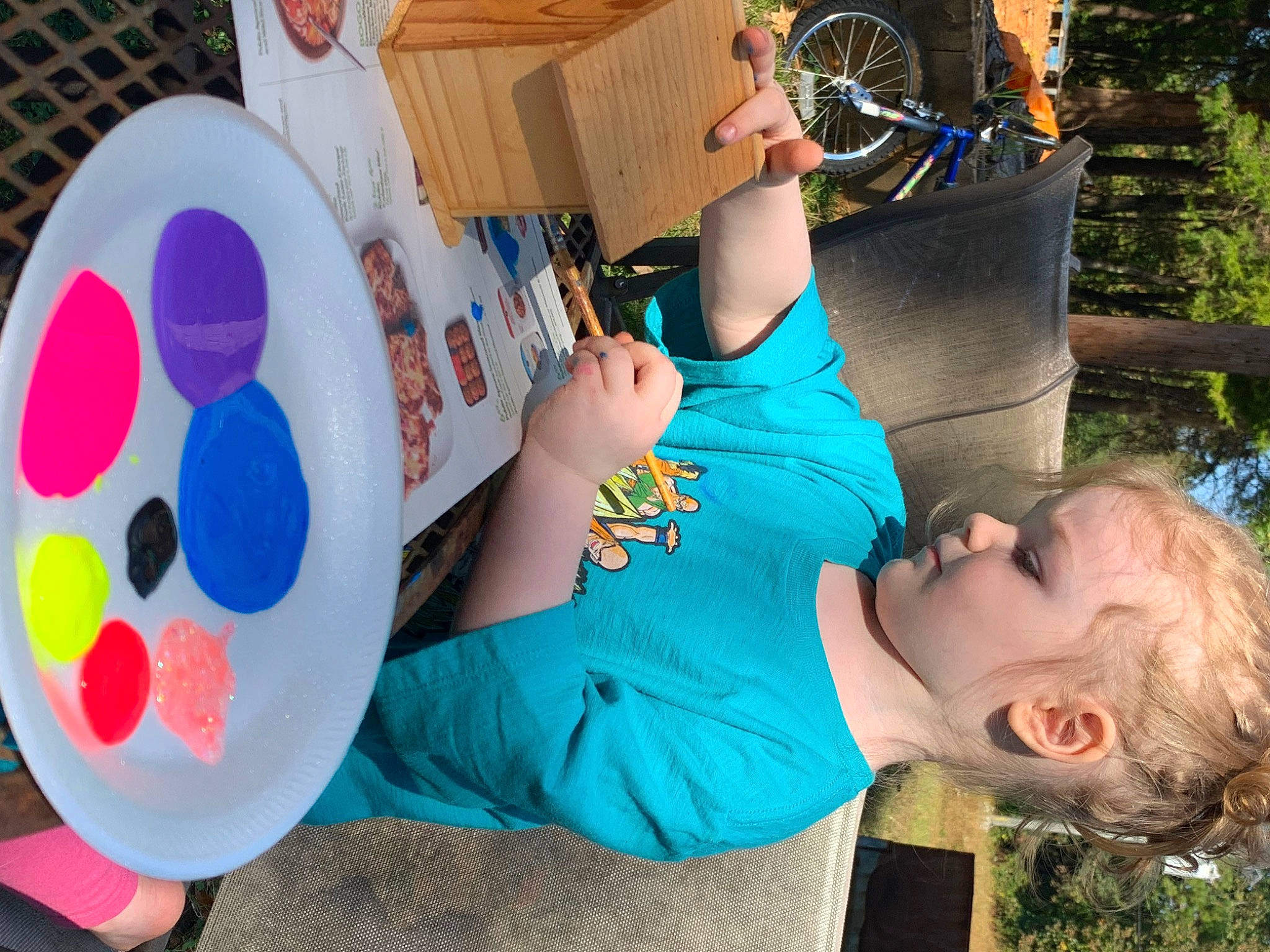 Mara is registered to the contest to win money with this photo: bicycle_wheel, chair, child, event, fun, grass, happy, hat, house, leisure, party_supply, person, plant, play, recreation, sitting, t_shirt, tire, toddler, tree