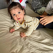Giulia participe au concours pour gagner de l'argent avec cette photo : child, baby, bed, pillow, bedding, striped_shirt, big_eyes, hair_tie, smile, hands, person, portrait, indoor, playful, sibling, blanket, couch, casual_clothing, curious, soft_light
