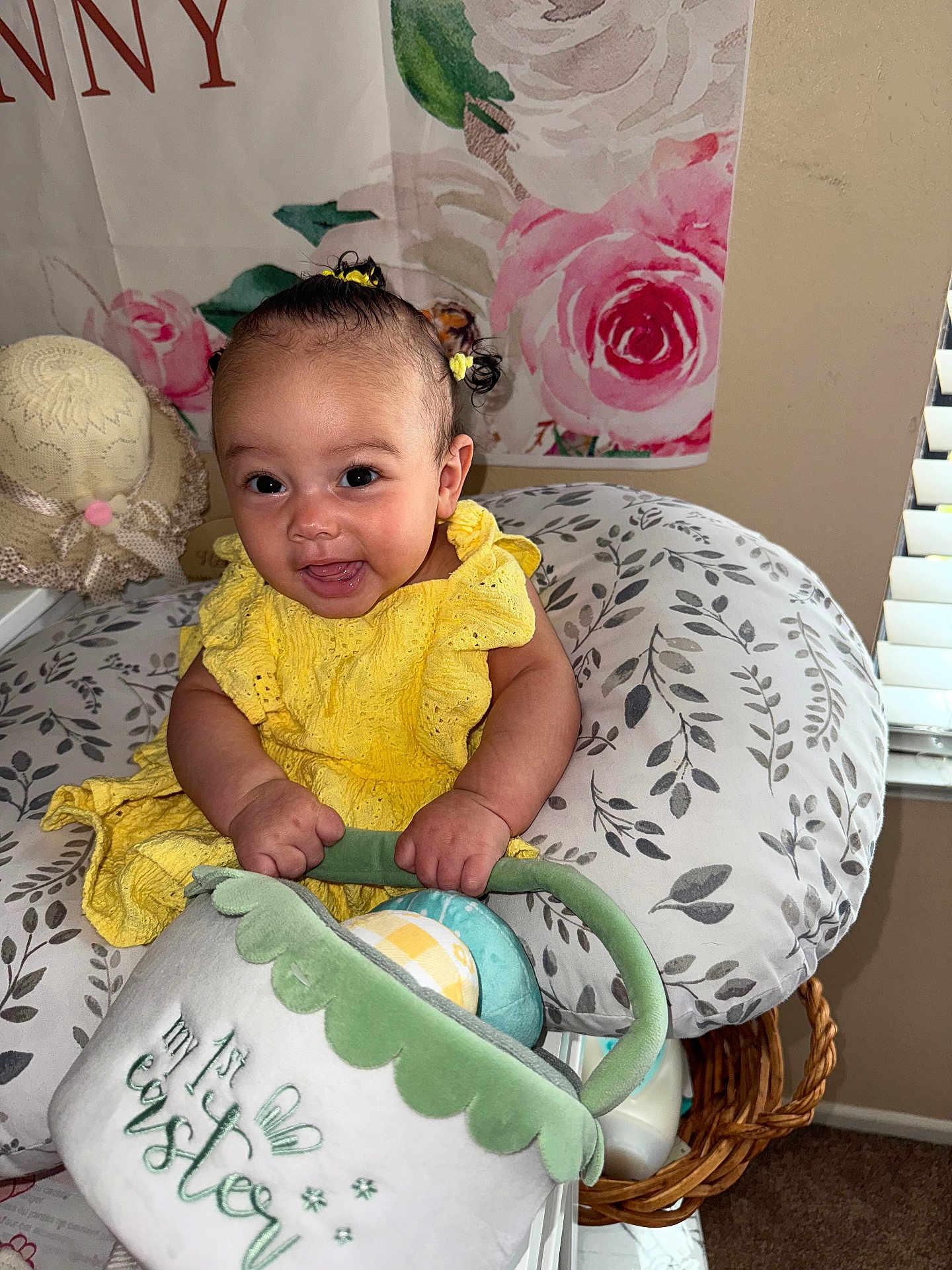 Amira is registered to the contest to win money with this photo: baby, child, yellow_dress, smiling, happy, toy, soft_toy, basket, home_interior, cushion, floral_pattern, hair_bows, infant, cute, decor, woven_basket, window_blinds, playful, portrait, indoors
