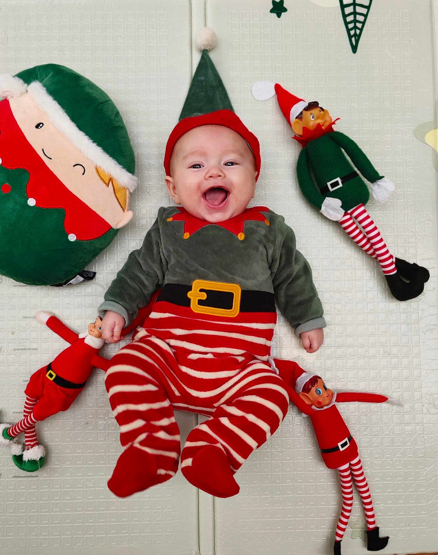 ézïo participe au concours pour gagner de l'argent avec cette photo : baby, smiling, elf_costume, red_and_white_stripes, green_clothing, holiday, christmas, plush_toys, elf_dolls, pillow, happy, infant, lying_down, cute, festive, indoor, child, toy, face, red_hat