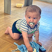 Kelohann a rejoint le concours — aidez-le/la à gagner de superbes lots ! baby, crawling, pacifier, striped_shirt, blue_blanket, remote_control, wooden_floor, indoors, child, cute, toddler, toy, flooring, clothing, person, young_child, home, curious, infant, playful