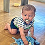 baby, crawling, pacifier, striped_shirt, blue_blanket, remote_control, wooden_floor, indoors, child, cute, toddler, toy, flooring, clothing, person, young_child, home, curious, infant, playful