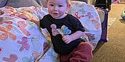 Brooklynn joined the competition — help win amazing prizes! toddler, child, indoor, living_room, sofa, cushion, braided_hair, barbie_tshirt, pants, barefoot, toy, carpet, bin, chair, wall_art, person, young_child, home, playful, smiling