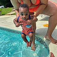 Khalid is registered to the contest to win money with this photo: baby, child, pool, water, swimsuit, tattoo, adult, hand, feet, outdoor, sunny, concrete, grass, steps, person, blue, orange, playing, summer, swimming