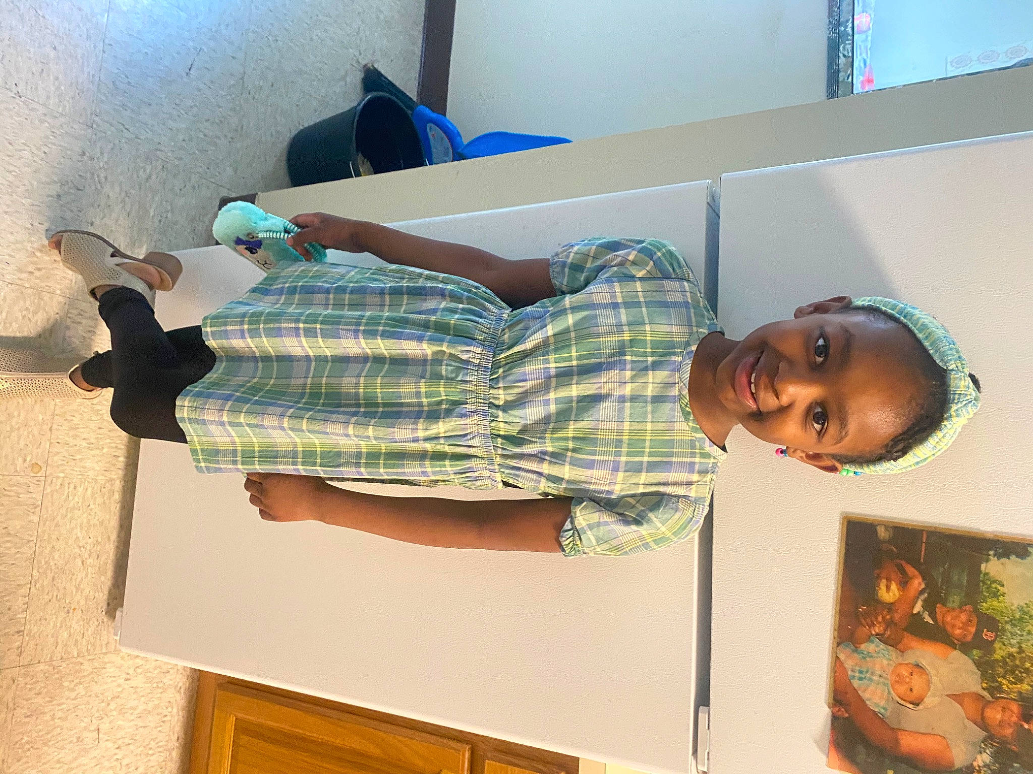 Ariya is registered to the contest to win money with this photo: art, child, comfort, elbow, flooring, fun, headwear, human_leg, joy, knee, linens, pattern, person, plaid, room, sandal, smile, textile, thigh, visual_arts