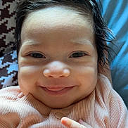 Khalyssa a rejoint le concours — aidez-le/la à gagner de superbes lots ! baby, blanket, child, closeup, cute, dark_hair, face, hands, happy, indoors, infant, lying_down, patterned_blanket, person, pink_clothing, portrait, ribbed_fabric, skin, smiling, soft_light