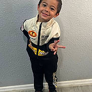 Anthony joined the competition — help win amazing prizes! child, boy, smiling, portrait, standing, peace_sign, racing_suit, jumpsuit, sportswear, sneakers, indoor, wall, floor, fashion, happy, pose, short_hair, full_body, casual, photography
