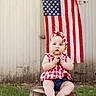 Blair joined the competition — help win amazing prizes! baby, child, infant, portrait, sitting, wooden_stool, american_flag, patriotic, gingham, headband, red_white_blue, outdoor, grass, rustic, barn, wooden_wall, blue_eyes, serious_expression, barefoot, photography