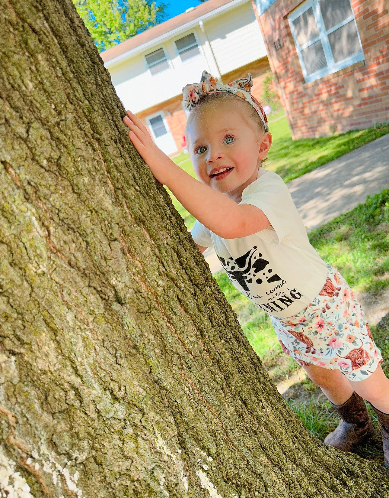 Addy is registered to the contest to win money with this photo: eyewear, fun, grass, hairstyle, happy, house, joy, leaf, leisure, people_in_nature, person, plant, recreation, sandal, sitting, smile, t_shirt, toddler, tree, trunk