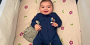 Noa participe au concours pour gagner de l'argent avec cette photo : baby, infant, smiling, crib, mattress, onesie, navy_onesie, blanket, lovey, floral_sheet, playpen, hair_tuft, face, eyes_open, hands, feet, lying_down, nursery, soft_fabric, cozy