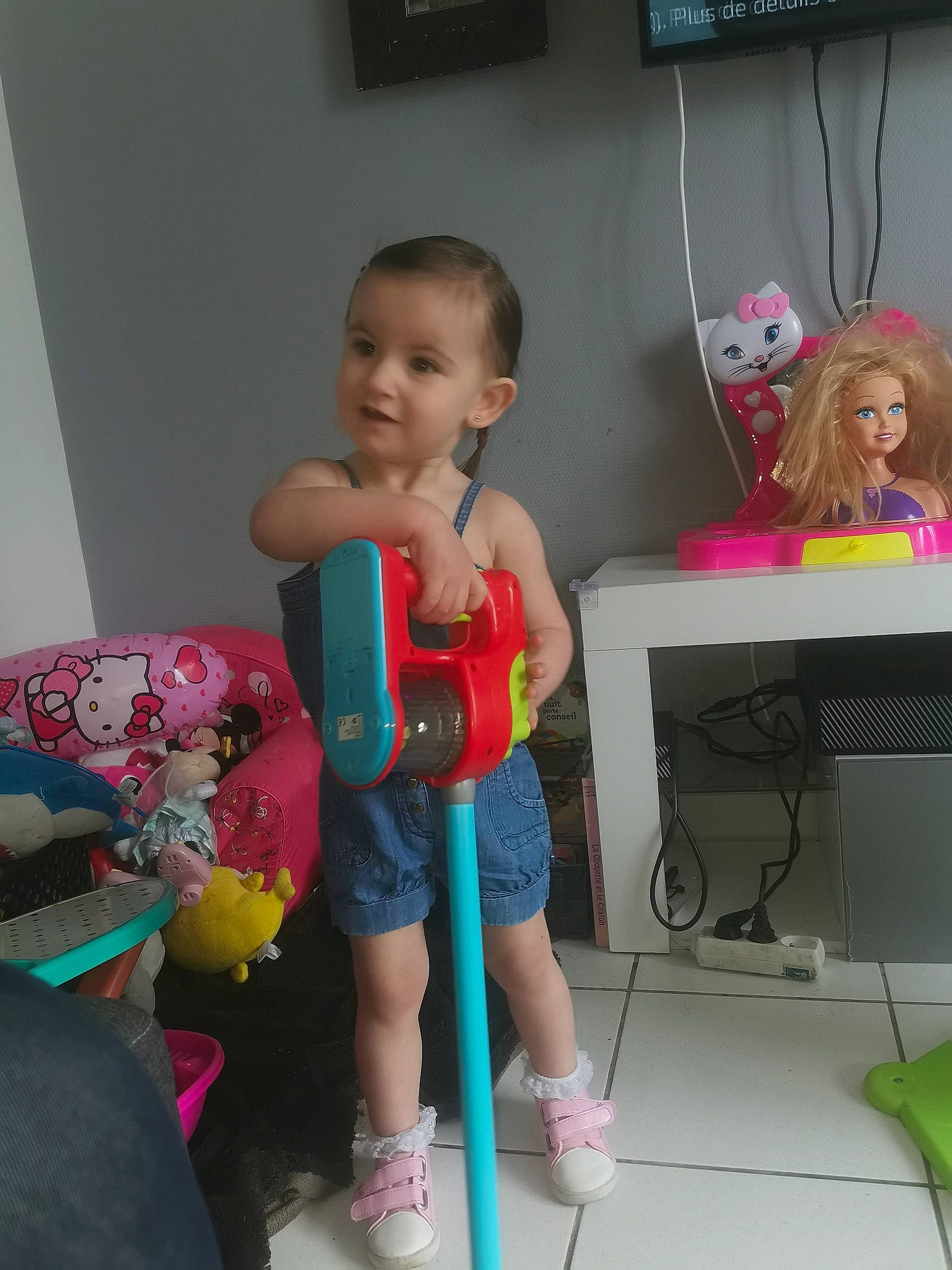 Maëlya participe au concours pour gagner de l'argent avec cette photo : baby_products, chair, child, computer_desk, desk, flooring, fun, hat, person, play, room, shelving, shorts, sitting, standing, stuffed_toy, sun_hat, table, thigh, toddler