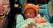 Christopher joined the competition — help win amazing prizes! baby, car_seat, blanket, crochet, hat, orange, infant, child, indoor, person, cozy, cute, resting, small, wrapped, seat, headwear, newborn, comfort, sleepy