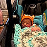 baby, car_seat, blanket, crochet, hat, orange, infant, child, indoor, person, cozy, cute, resting, small, wrapped, seat, headwear, newborn, comfort, sleepy