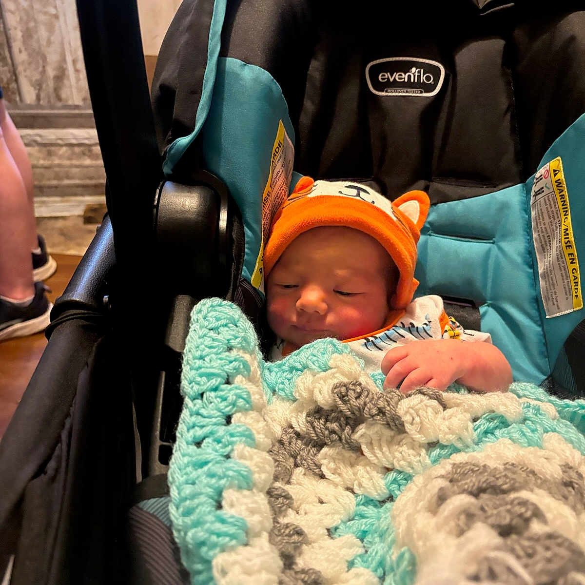 Christopher joined the competition — help win amazing prizes! baby, car_seat, blanket, crochet, hat, orange, infant, child, indoor, person, cozy, cute, resting, small, wrapped, seat, headwear, newborn, comfort, sleepy