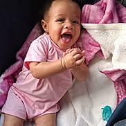 Delayah Brown is registered to the contest to win money with this photo: baby, infant, smiling, clapping, pink_clothing, blanket, soft_texture, happy, cute, child, indoors, portrait, face, person, newborn, lying_down, pacifier, cozy, toddler, joyful