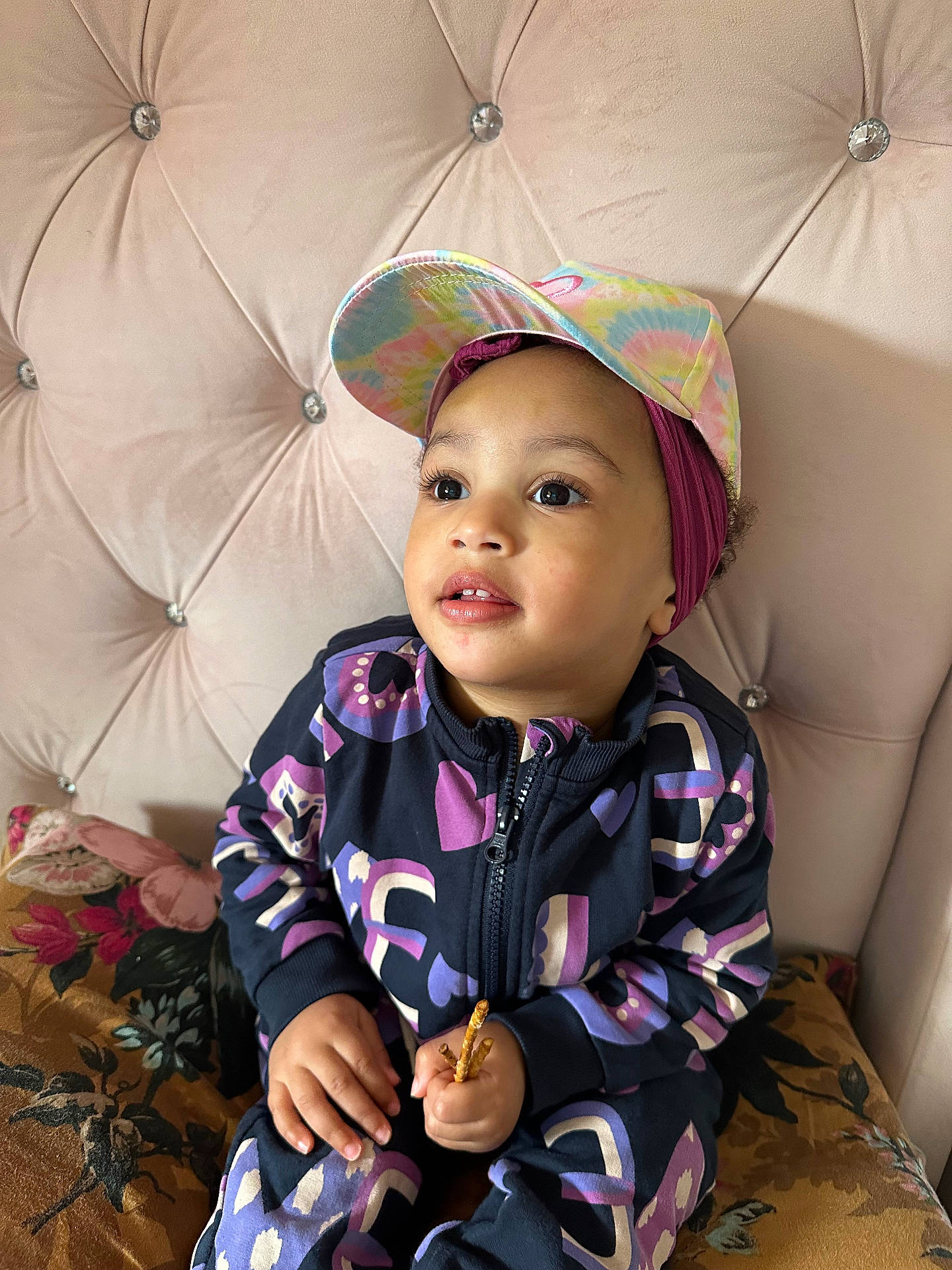 Abigail is registered to the contest to win money with this photo: baby, baseballcap, bodypart, cap, clothing, coat, couch, face, finger, furniture, hand, happy, hat, head, jacket, person, photography, portrait, sitting, smile